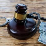 judge-s-gavel-dollars-handcuffs-wooden-table_357889-3931