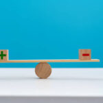 Wooden seesaw with plus and minus sign.