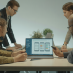 High-quality hero photograph of developers collaborating on mobile app development at a modern workspace with laptop and design sketches